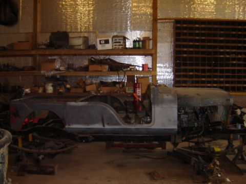 1992 Ford Bronco - The body of a Jeep CJ-6 sits on stands in a cluttered workshop, awaiting restoration.