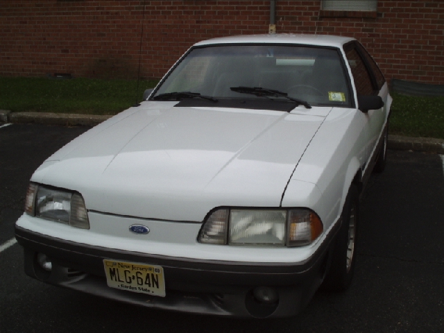 White 1989 Ford Mustang GT parked in front of a brick building