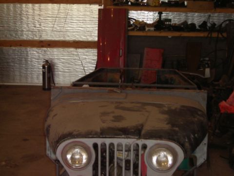 1992 Ford Bronco - The front clip of a vintage Jeep CJ-5 sits in a workshop, awaiting restoration.