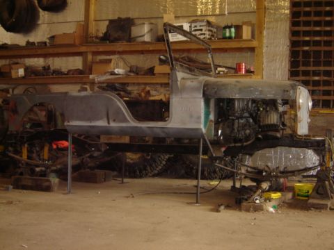 1992 Ford Bronco - A Jeep CJ-6 body is shown on stands in a workshop, with its engine and chassis components visible.