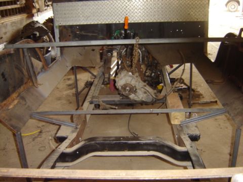 1992 Ford Bronco - Engine and transmission assembly suspended over a vehicle frame during restoration or modification.