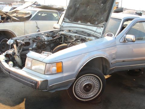 1993 Ford Taurus - This light blue sedan has its hood open, revealing the engine compartment. Another vehicle is visible behind it.