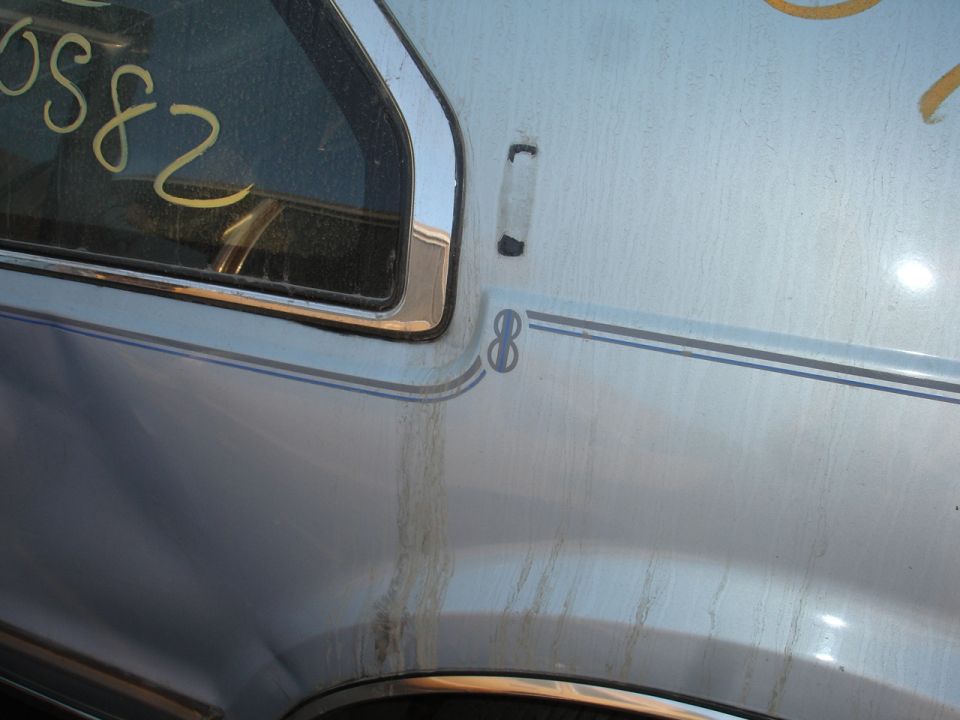 Light blue car door with chrome trim, a dark stripe with an '8' emblem, and yellow writing on the window
