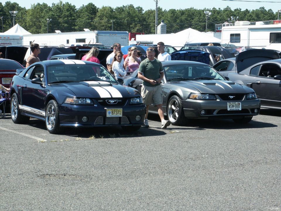 Dark blue Ford Mustang with white stripes, front 3/4 view