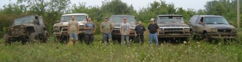1979 Ford Bronco - A group of people and their muddy off-road vehicles are gathered in a field.