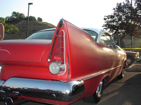 1979 Ford Bronco - Rear view of a red 1957 Plymouth Fury, notable for its distinctive tail fins and chrome bumper, parked outdoors.