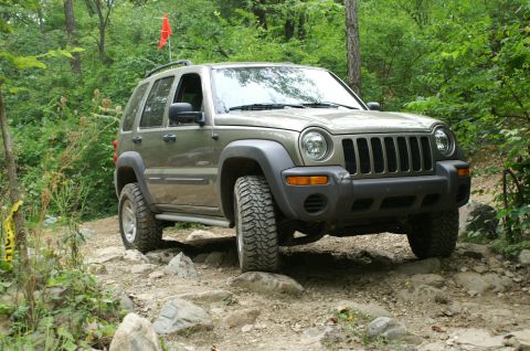 2006 Jeep Liberty - A Jeep Liberty navigates a challenging rocky path, its tires gripping the uneven terrain.