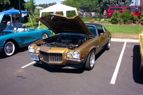 1970 Chevrolet Camaro - A gold 1970 Chevrolet Camaro is displayed with its hood open at an outdoor car show.