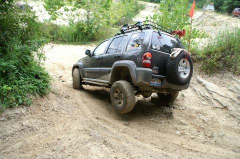 2006 Jeep Liberty - A dark gray 2006 Jeep Liberty navigates a challenging dirt trail with a spare tire mounted on the rear.