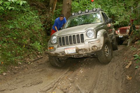 2006 Jeep Liberty - A 2006 Jeep Liberty tackles a challenging muddy trail, with a second Jeep visible in the background.