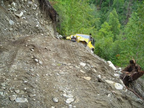 2003 Jeep TJ - Yellow 2003 Jeep TJ navigating a challenging off-road terrain on a steep, rocky slope.