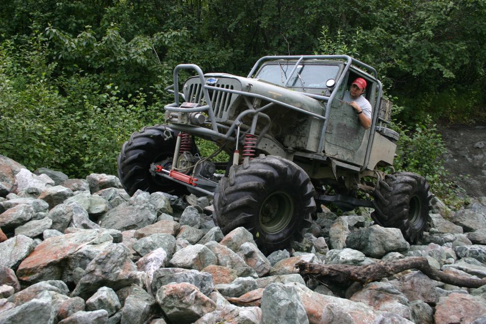 Modified Jeep CJ-series with large tires and roll cage driving over rocks