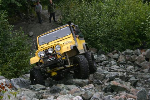 2003 Jeep TJ - Yellow Jeep CJ tackling a difficult rocky terrain course.