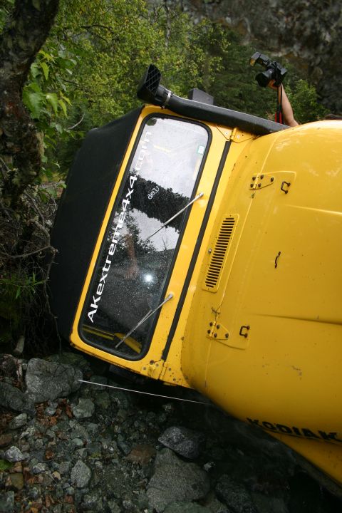 2003 Jeep TJ - This yellow off-road vehicle has tipped onto its side in a rocky, wooded area.