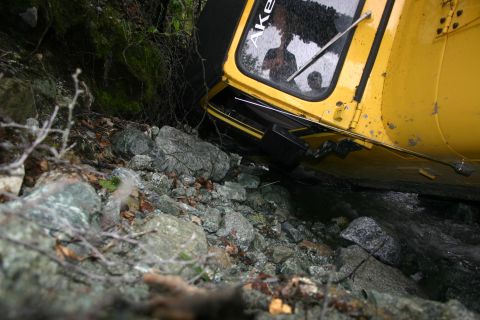 2003 Jeep TJ - A yellow vehicle is stuck in a rocky ravine next to a stream.