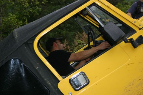 2003 Jeep TJ - Driver inside a yellow Jeep Wrangler, likely a 2003 model, during an off-road excursion.