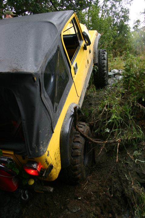 2003 Jeep TJ - Yellow 2003 Jeep TJ with soft top is stuck in mud on an off-road trail.