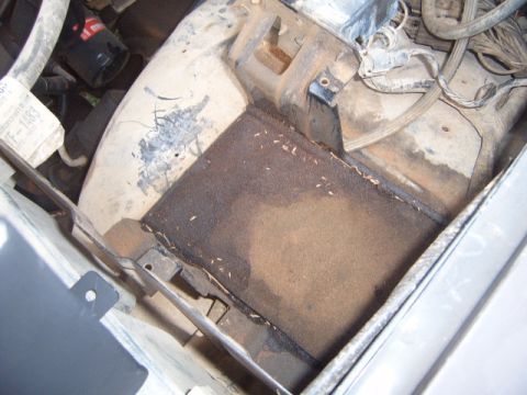 1988 Ford Bronco - Close-up view of engine bay components, including hoses, wires, and a filter, with visible dirt and debris.