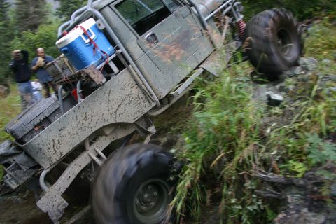 2003 Jeep TJ - This vehicle is navigating a challenging off-road trail, with its tires struggling for traction on the steep, wet terrain.