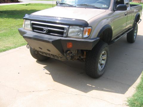 1999 Toyota Tacoma - A tan Toyota Tacoma pickup truck is shown from the front with an aftermarket bumper and bug deflector.