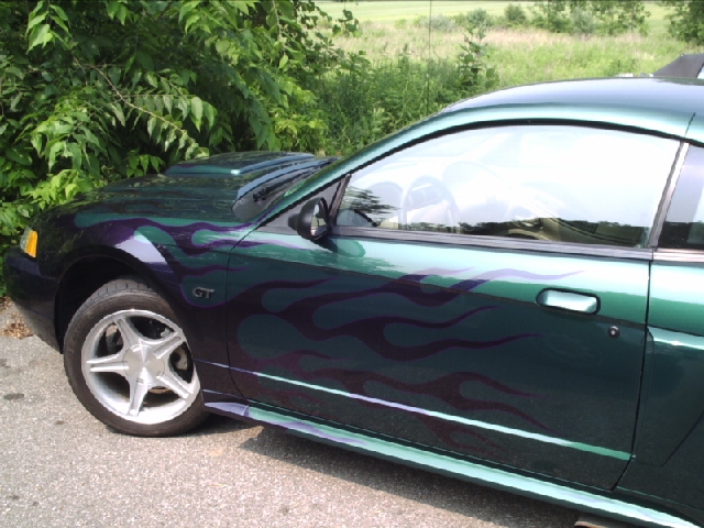 Green Ford Mustang with purple flame decals, side view, showing hood scoop and GT badge