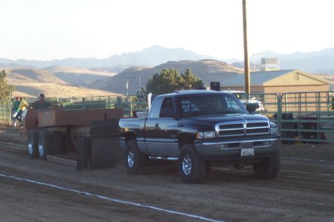 1994 Ford F-150 - A black Dodge Ram pickup truck competes in a truck pull event, towing a heavy trailer.