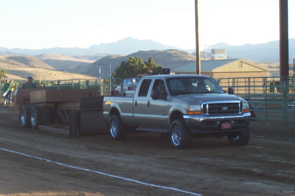 Silver Ford F-250 Super Duty truck pulling a trailer in a dirt arena