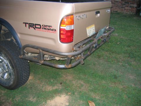 1999 Toyota Tacoma - Rear view of a tan Toyota Tacoma pickup truck with a TRD Off Road decal and a custom metal bumper.