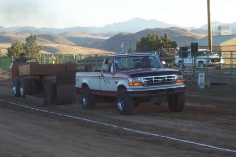1994 Ford F-150 - A modified Ford F-150 competes in a truck pull event, dragging a weighted sled across a dirt track.
