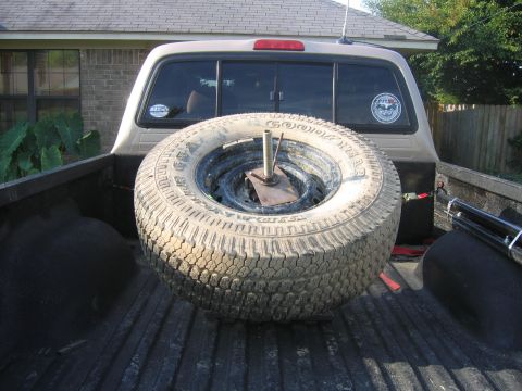 1999 Toyota Tacoma - Spare tire dominates the view inside the bed of a pickup truck.