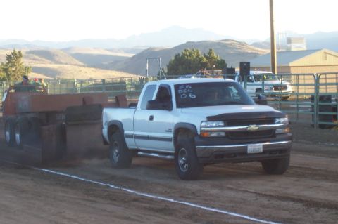 1994 Ford F-150 - A white Chevrolet Silverado truck competes in a pull event, dragging a sled across the dirt track.