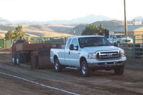 1994 Ford F-150 - White pickup truck competes in a pull event, with another truck visible in the background.