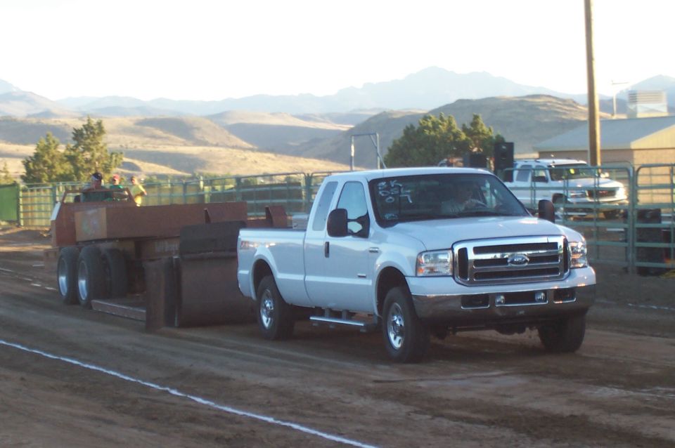 White pickup truck pulling a sled, 3q-front view. Text on windshield