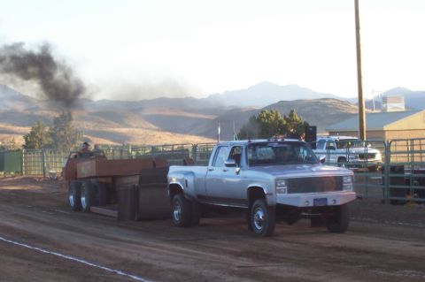 1994 Ford F-150 - A silver dually pickup truck pulls a trailer, kicking up dust and smoke during an event.