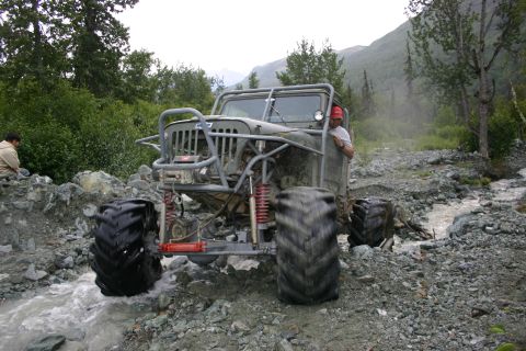 2003 Jeep TJ - Custom Jeep CJ-7 navigates a challenging off-road terrain with a stream running through rocks.