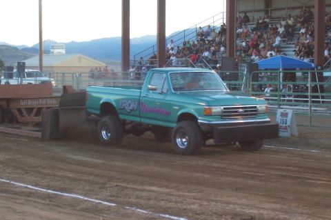 1994 Ford F-150 - A lifted Ford F-150 truck competes in a truck pull event, with spectators in the background.