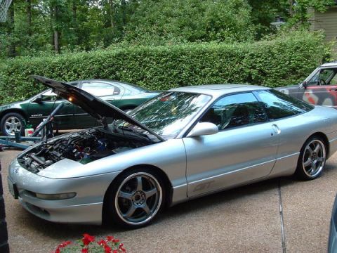 1993 Ford Probe - A silver 1993 Ford Probe GT is parked with its hood open, revealing the engine bay, with another car visible in the background.