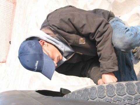 1991 Ford Explorer - A person works on a tire, with a visible "SUPERMOTORS" logo on the vehicle part.