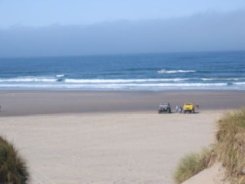 1991 Ford Explorer - Two SUVs are parked on a sandy beach with the ocean and waves in the background.
