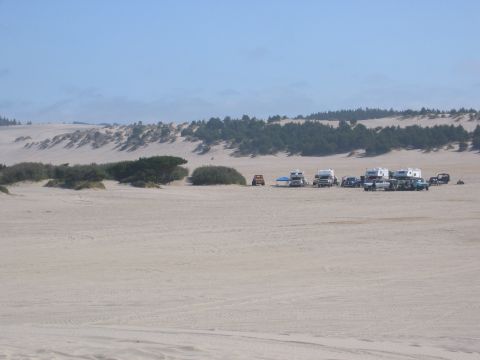 1991 Ford Explorer - A group of RVs and vehicles are parked on sand dunes under a clear sky.
