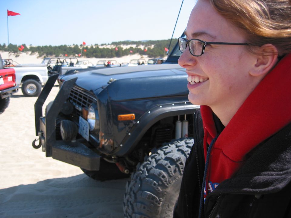 Black Ford Bronco with custom bumper and large tires, parked on sand dunes