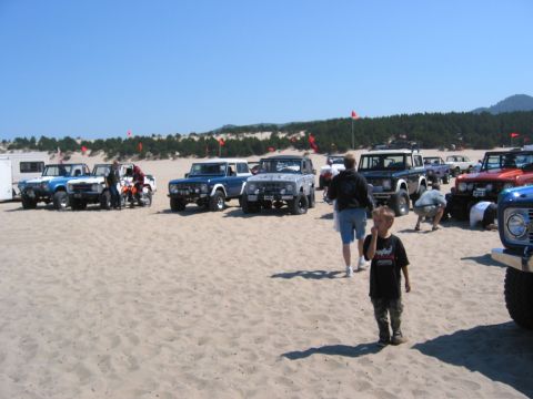 1991 Ford Explorer - A collection of off-road vehicles gathered on a sandy beach under a clear blue sky.