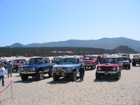 1991 Ford Explorer - A collection of Ford Broncos gathered on a sandy terrain under a clear blue sky.