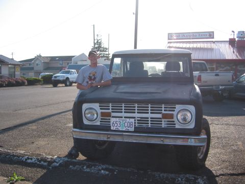 1991 Ford Explorer - Person leaning on a classic Ford Bronco parked in front of a building. Other vehicles are visible in the background.