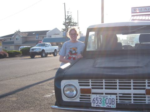 1991 Ford Explorer - A person poses with a classic Ford Bronco, with a white pickup truck visible in the background.