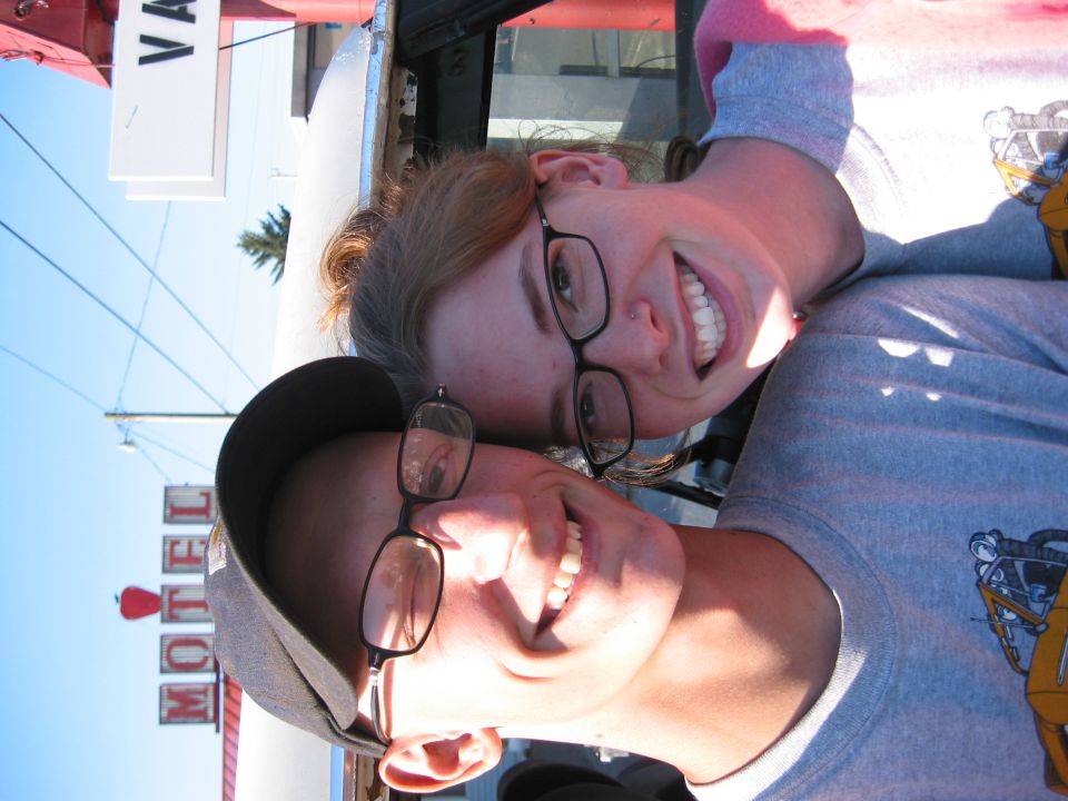 Two smiling people in front of a motel sign