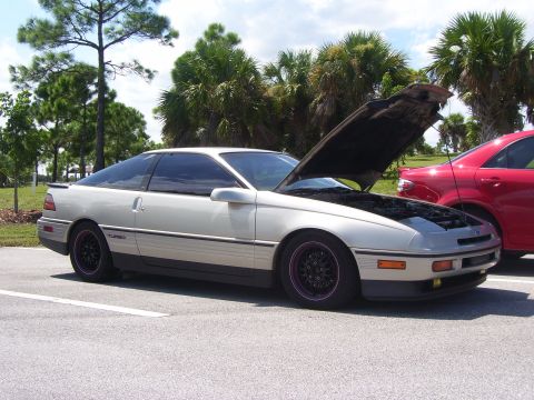 1994 Ford Probe - A silver Ford Probe is parked with its hood up, revealing the engine bay. Another car is visible to the right.