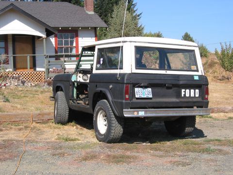 1991 Ford Explorer - A black and white Ford Bronco is parked in front of a house, showing its rear and side profile.