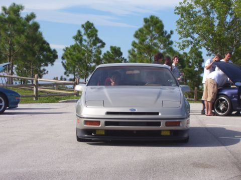 1994 Ford Probe - A silver Ford Probe is parked outside with other cars and people around.