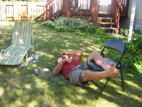 1995 Ford Bronco - A man rests on the lawn in a backyard setting, surrounded by empty beverage containers and outdoor furniture.